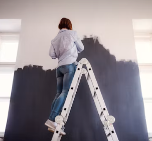 Peintre appliquant de la peinture blanche au rouleau sur un mur intérieur
